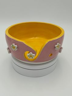 a yellow and pink bowl sitting on top of a white box with flowers painted on it