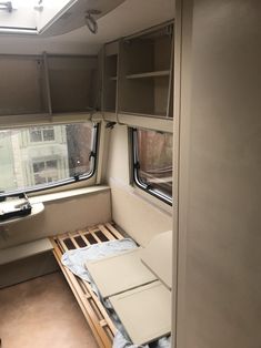 the inside of a camper with windows and wooden slats on the bed area