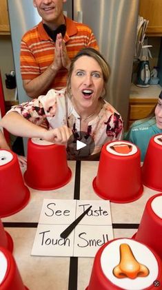 a group of people sitting around a table with red cups on it and one person standing in front of them