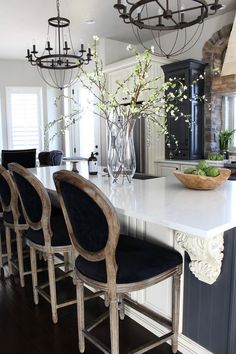 a large kitchen island with chairs and a bowl of flowers on it's counter