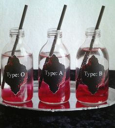 three glass bottles filled with red liquid and two black straws on top of each one