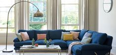 a living room filled with blue couches and pillows on top of a wooden floor