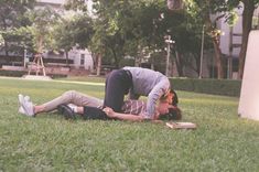 a woman laying on the ground next to a man with a book in his lap