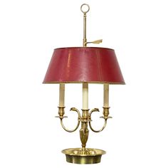 a brass table lamp with a red shade