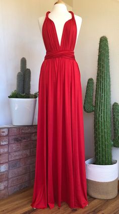 a red dress is displayed on a mannequin in front of cacti