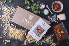 pasta ingredients laid out on top of a black surface with basil, sunflower seeds and seasonings