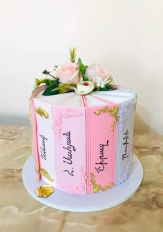 a cake decorated with books and flowers on a table