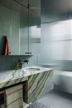 a bathroom with a marble sink and green tiled walls in the shower area is shown