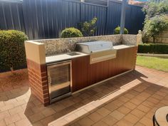 an outdoor bbq and grill area in a backyard with brick pavers flooring