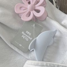 a pink and blue dolphin toy next to a white t - shirt with a tag on it