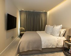 a bedroom with a bed, chair and television on the wall in front of it