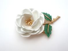 Vintage Floral Jewelry - This is a gold tone brooch with white enamel flower and green enamel leaves. It is signed Trifari with a crown over the T and measures almost 2.25" by 1.25". White Enamel Brooch Jewelry, Elegant White Enamel Pin, Formal White Enamel Pin Brooch, Formal White Enamel Pin, Vintage White Enamel Brooches, White Vintage Enamel Brooches, Vintage White Enamel Pin, Flower-shaped Enamel Brooches For Wedding, Flower Shaped Enamel Brooches For Wedding