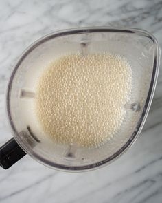 a blender filled with white liquid on top of a marble counter