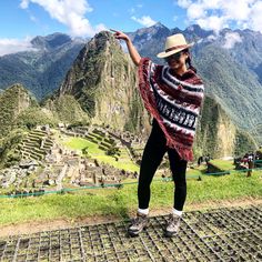 a woman standing on top of a metal grate in front of a mountain range