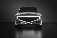 the front end of a silver car in a dark room