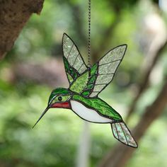 a stained glass hummingbird ornament hanging from a tree