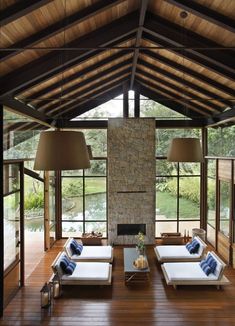 a living room filled with lots of furniture under a wooden roof over looking a lake