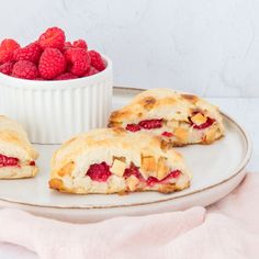 raspberry pastries on a plate with a bowl of raspberries