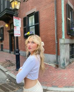 a woman standing in front of a brick building next to a street light and lamp post