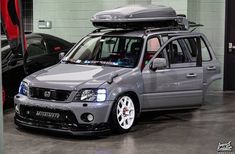 a silver car with a surfboard on top of it's roof rack in a garage