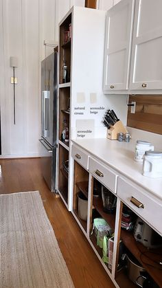 a kitchen with white cabinets and wood flooring next to a large refrigerator freezer