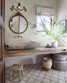 a bathroom with a sink, mirror and stool next to a potted plant on the counter