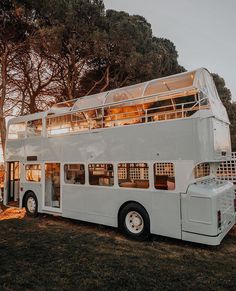 a white double decker bus parked in the grass