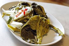 a white plate topped with green vegetables on top of a table