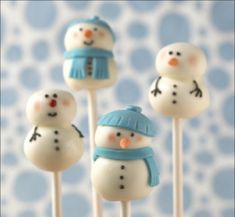 four snowman lollipops sitting on top of each other in front of a blue and white wall