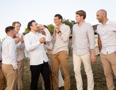 a group of men standing next to each other on top of a grass covered field