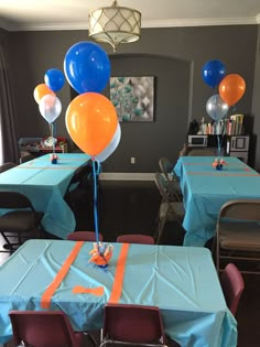 balloons and streamers are on the table for an orange and blue themed birthday party