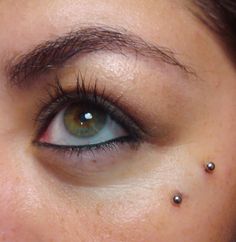 a woman with piercings on her eye looking at the camera