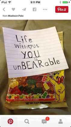 a bag of gummy bears sitting on top of a bed next to a sign