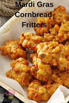 some food is sitting in a tray on a table with the words mardi gras cornbread fritters