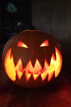 a carved pumpkin sitting on top of a table with its eyes glowing in the dark