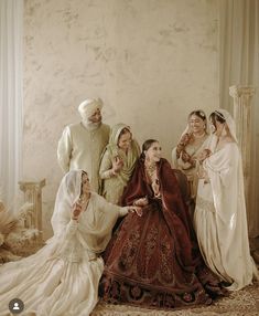 a group of people standing around each other posing for a photo in wedding dresses and turbans