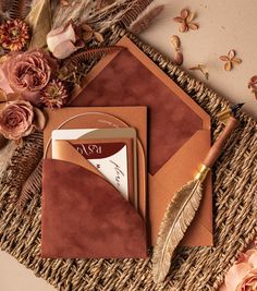 the wedding stationery is laid out on a wicker mat with flowers and feathers