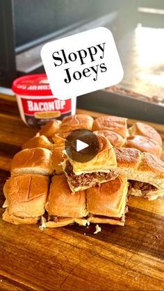 a pile of sliders sitting on top of a wooden cutting board next to a microwave