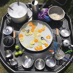 an outdoor table with pots and pans on it, lemon slices are arranged in the middle