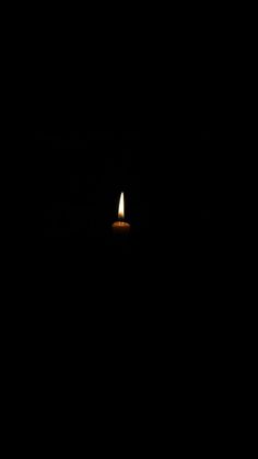 a candle is lit in the dark with only one light on it's side