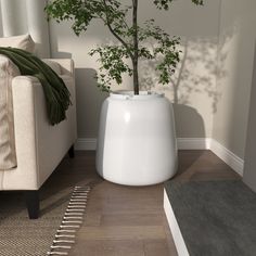 a white planter sitting next to a couch in a living room with wood flooring