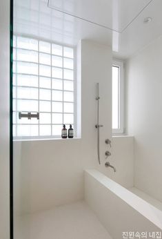 a white bathroom with a large window and shower head in the corner next to it