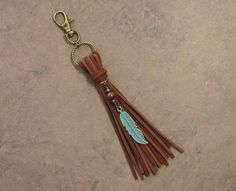 a brown leather tassel with a blue feather charm hanging from it's side