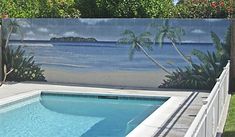 a pool with a painting on the side of it and palm trees in the background