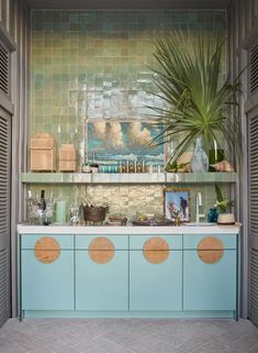 a kitchen with blue cabinets and green tile backsplash, potted plant on the counter