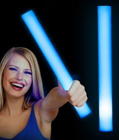 a woman is holding two blue lights in her hand and smiling at the camera with both hands