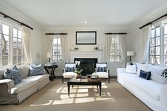 a living room filled with white couches and pillows on top of a carpeted floor