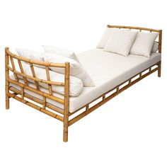 a bamboo bed frame with white pillows on it