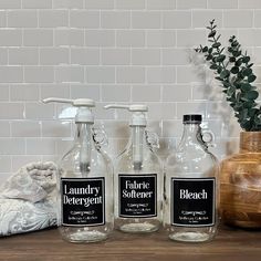 three empty bottles sitting on top of a wooden table next to a potted plant