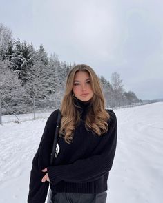 a woman standing in the snow with her hands on her hips and looking at the camera